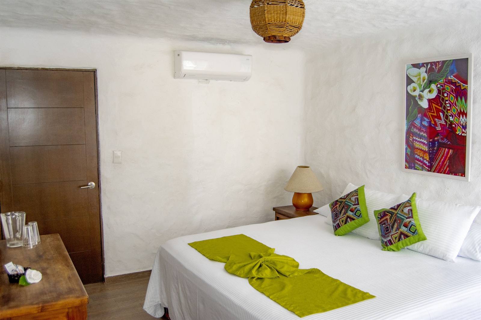 Petit Hotel Pilitas: King bedroom with white walls, a colorful painting and air conditioning